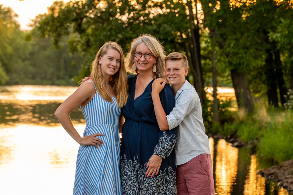Mom, daughter, and son standing near water with a golden sky